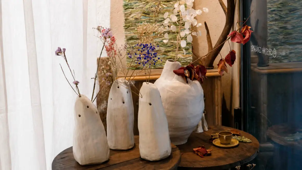 Creacions de ceràmica de Cristina Guillamet exposades al seu taller de Ripoll, amb peces blanques de formes orgàniques decorades amb flors seques.