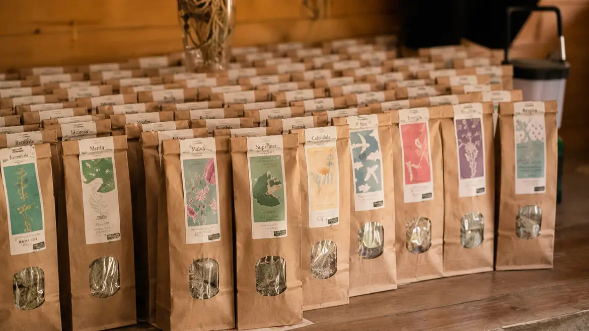 Bosses d’infusions i plantes aromàtiques seques exposades sobre un taulell de fusta, preparades per a la venda.