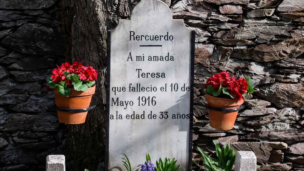 Detall de la làpida de Teresa a Bausen, amb la inscripció «A mi amada Teresa», la data de la seva mort, el 10 de maig de 1916, i la seva edat, 33 anys, envoltada de flors i del mur de pedra del petit cementiri.
