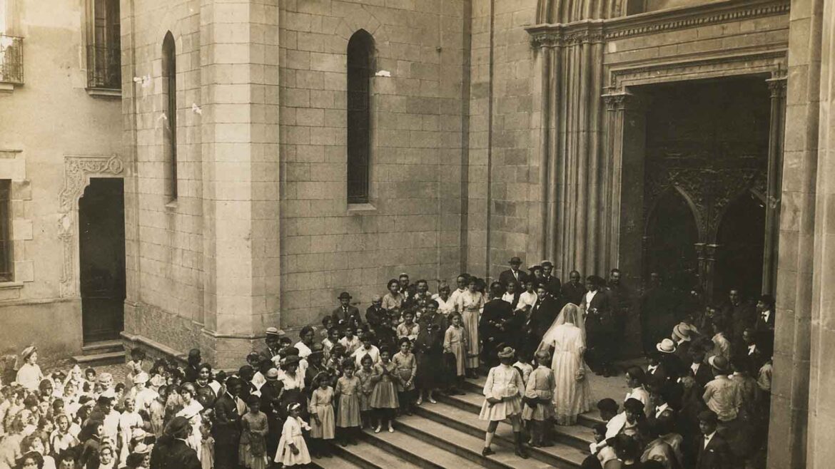 Celebració del casament de Laureà Dalmau i Laura Norat a l’església del Sagrat Cor de Girona l’any 1914, amb els nuvis envoltats de familiars, convidats i nombrosos veïns.