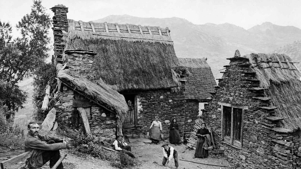 Família i habitants de Bordius, a Canejan, davant diverses bordes de pedra amb cobertes de palla, cap al 1907, en una escena de la vida quotidiana al Baish Aran.