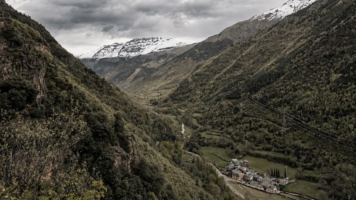 Vista de la Vall Fosca, amb els dos vessants, el fons de vall, els prats i un nucli habitat.