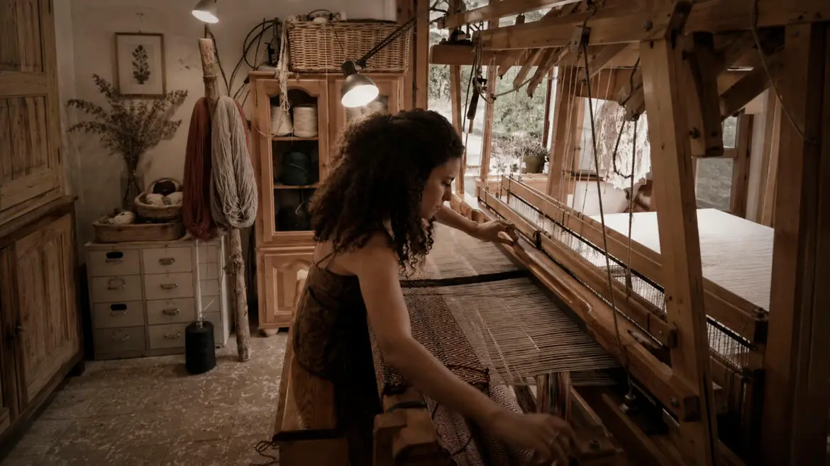 Summar treballant en un antic teler de fusta al seu taller GhusonArt, a la Pobla de Segur, on crea peces tèxtils artesanals amb llana.