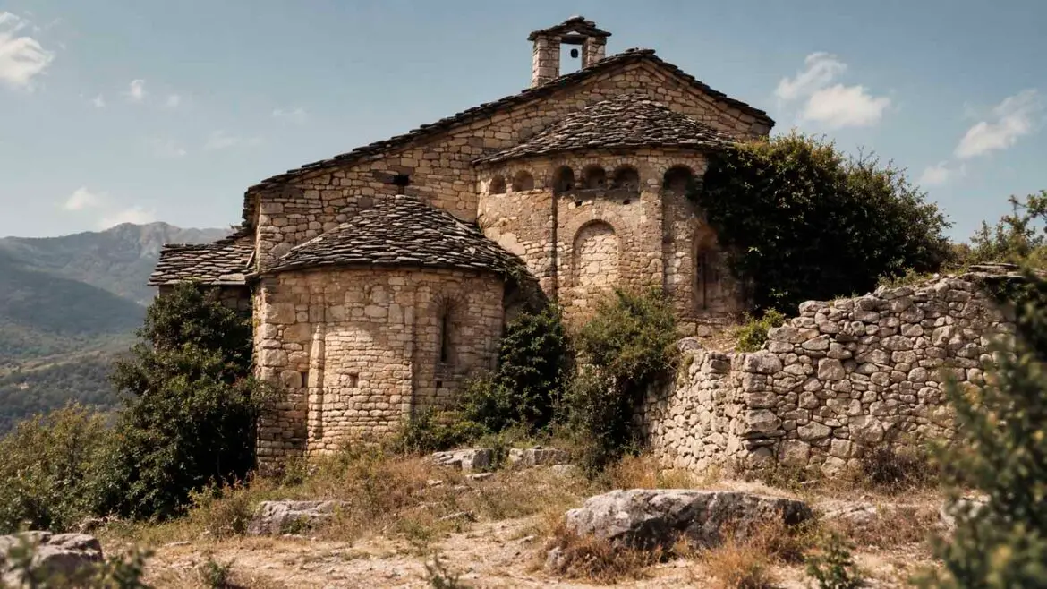 Vista exterior de la col·legiata de Santa Maria de Mur, al Pallars Jussà, amb els absis romànics, els murs de pedra i les restes del conjunt monumental.