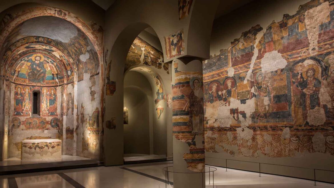 Recreació d’una sala dedicada a la pintura mural romànica del Museu Nacional d’Art de Catalunya, amb diversos conjunts pictòrics instal·lats sobre estructures que reprodueixen l’arquitectura original de les esglésies.