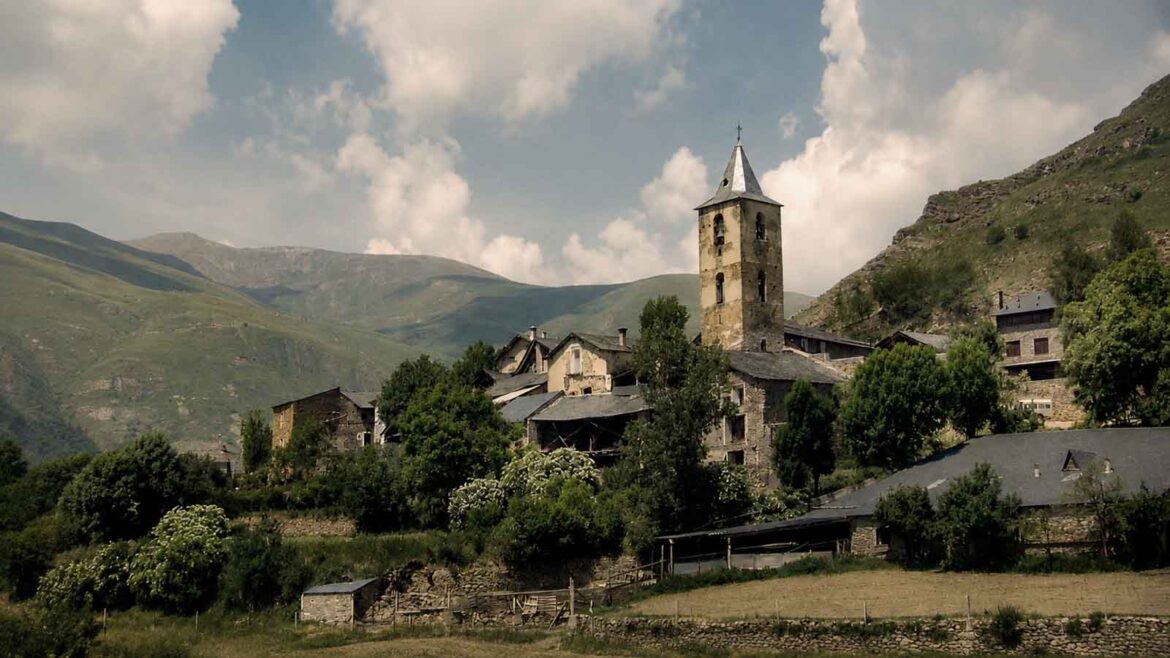 Vista panoràmica de Llessui, a la Vall d’Àssua, amb el campanar de l’església dominant les cases del poble i els vessants muntanyosos del Pallars Sobirà al fons.