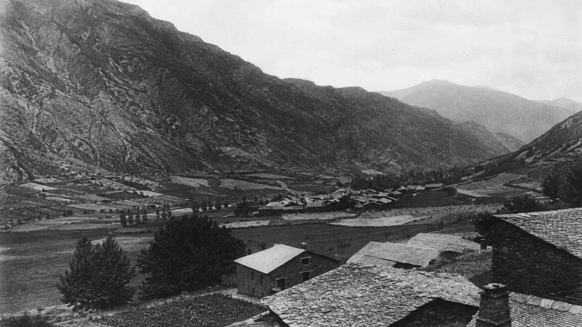 Vista d’Àreu des de la Força d’Àreu, a la Vall Ferrera, al Pallars Sobirà, amb el poble envoltat de camps i prats i les muntanyes pirinenques tancant la vall, l’any 1935.