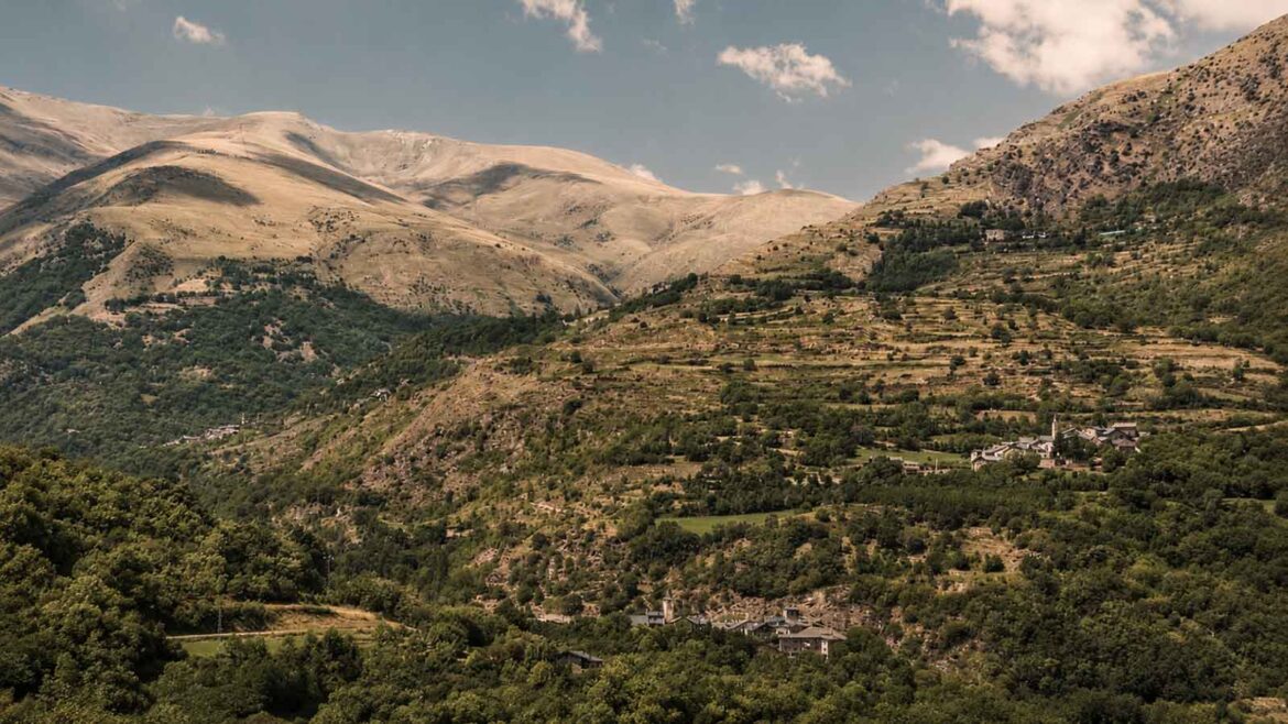 Vista panoràmica de la Vall d’Àssua, al Pallars Sobirà, amb els petits nuclis de Sorre, Altron i Bernui distribuïts entre boscos, prats i vessants de muntanya.