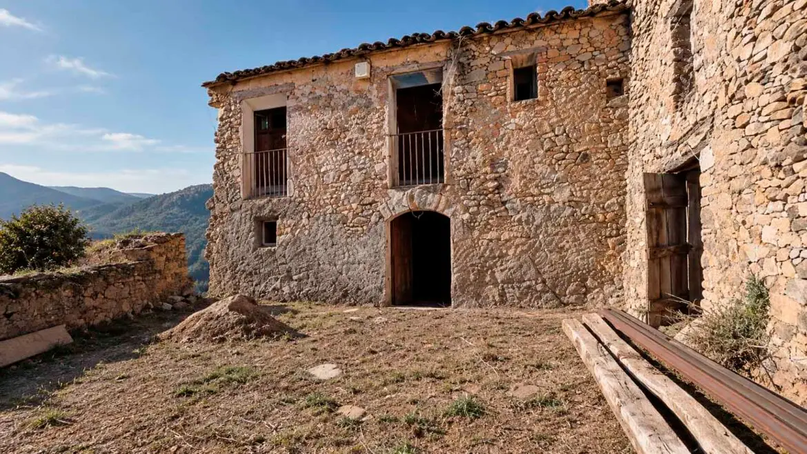Antiga casa pirinenca de pedra abans de la rehabilitació, amb l’era al davant i els espais inferiors tradicionalment vinculats als animals i a les activitats agrícoles.